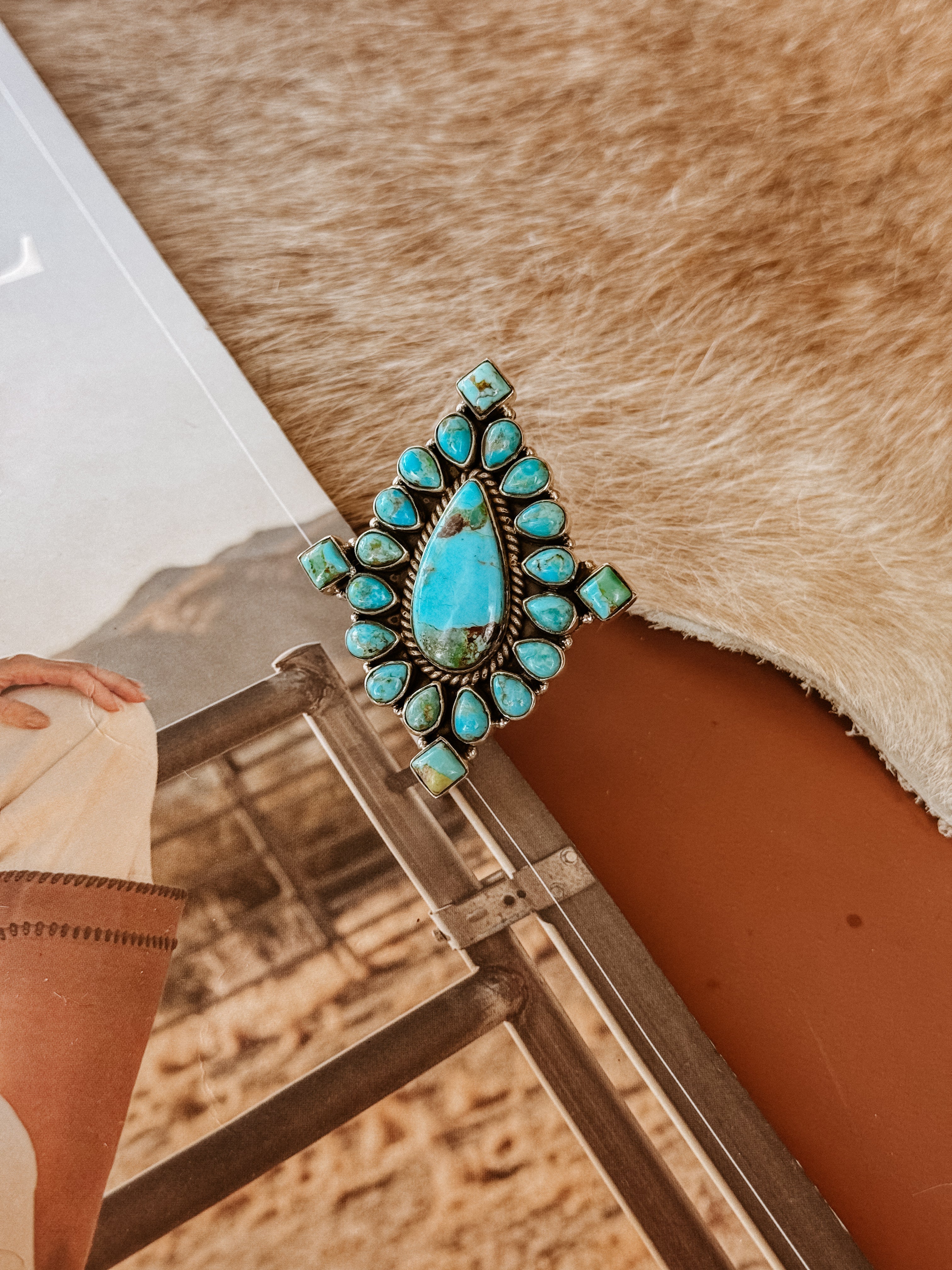 Western turquoise statement ring with silver setting on cowhide background, boho jewelry