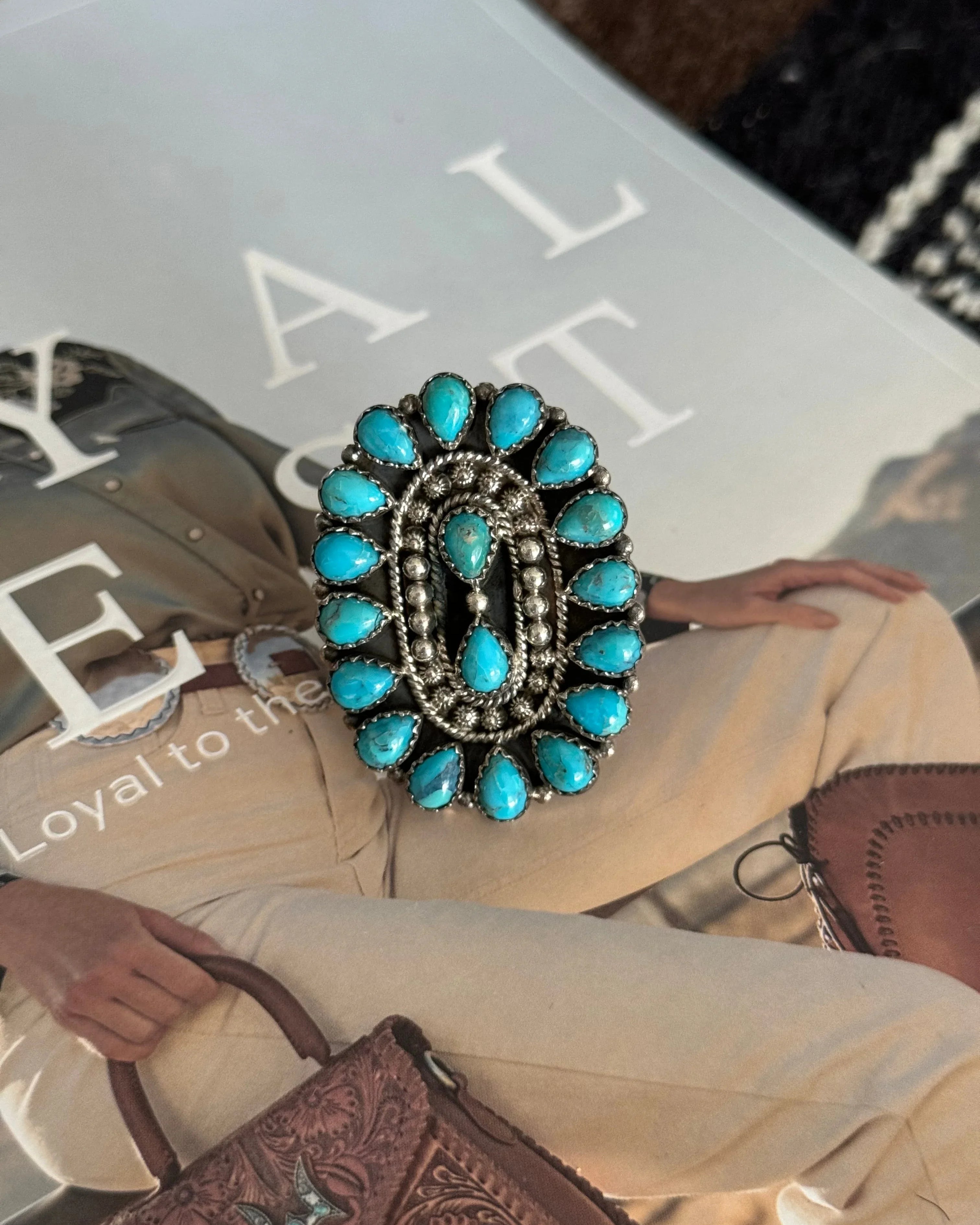 Western boho oval statement ring with turquoise stones on magazine background