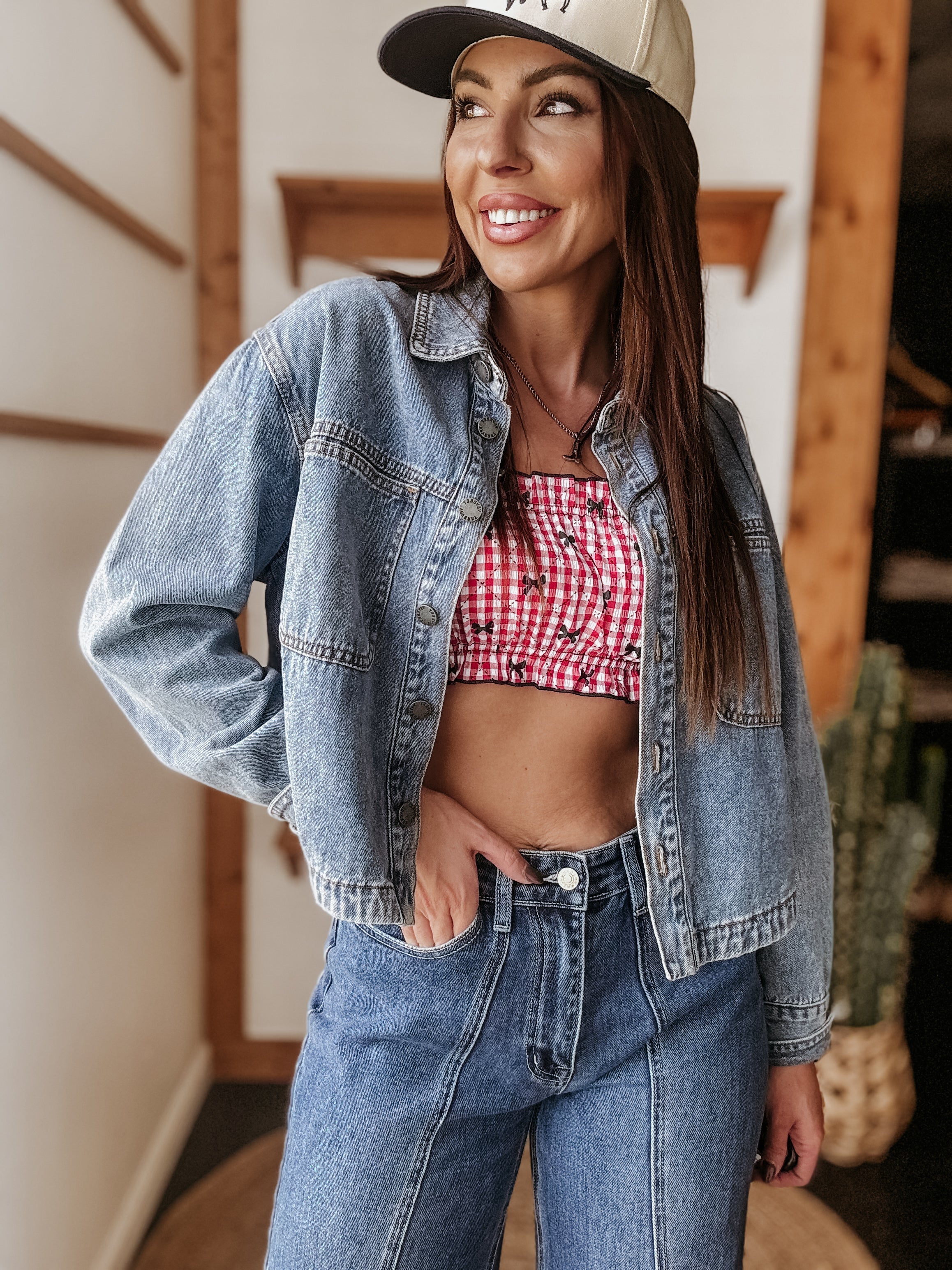 Woman in denim jacket and jeans, red gingham crop top, western hat, western boho style