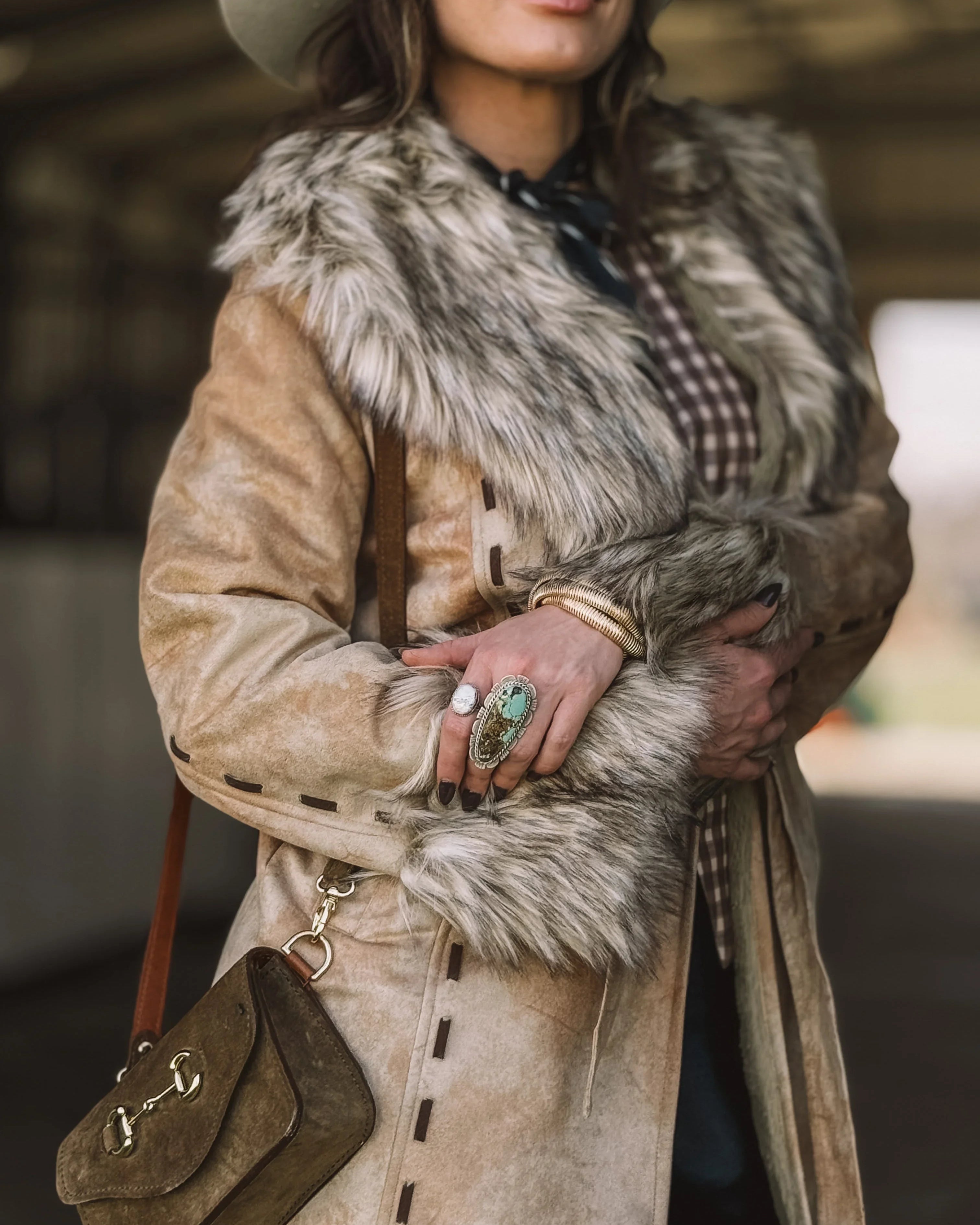 Woman in western fur-trimmed suede coat, turquoise ring, brown bag, cowgirl style