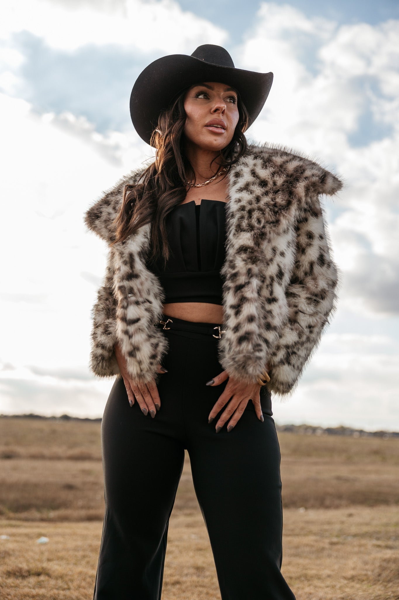 Woman in a cowboy hat and faux fur leopard print jacket, western boho outfit outdoors