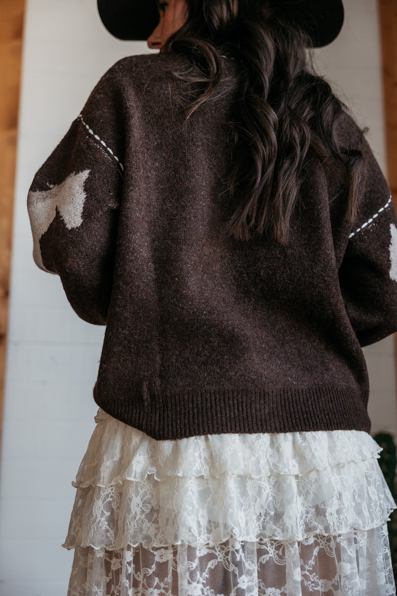 Woman in brown western sweater with white cow print details and layered lace skirt