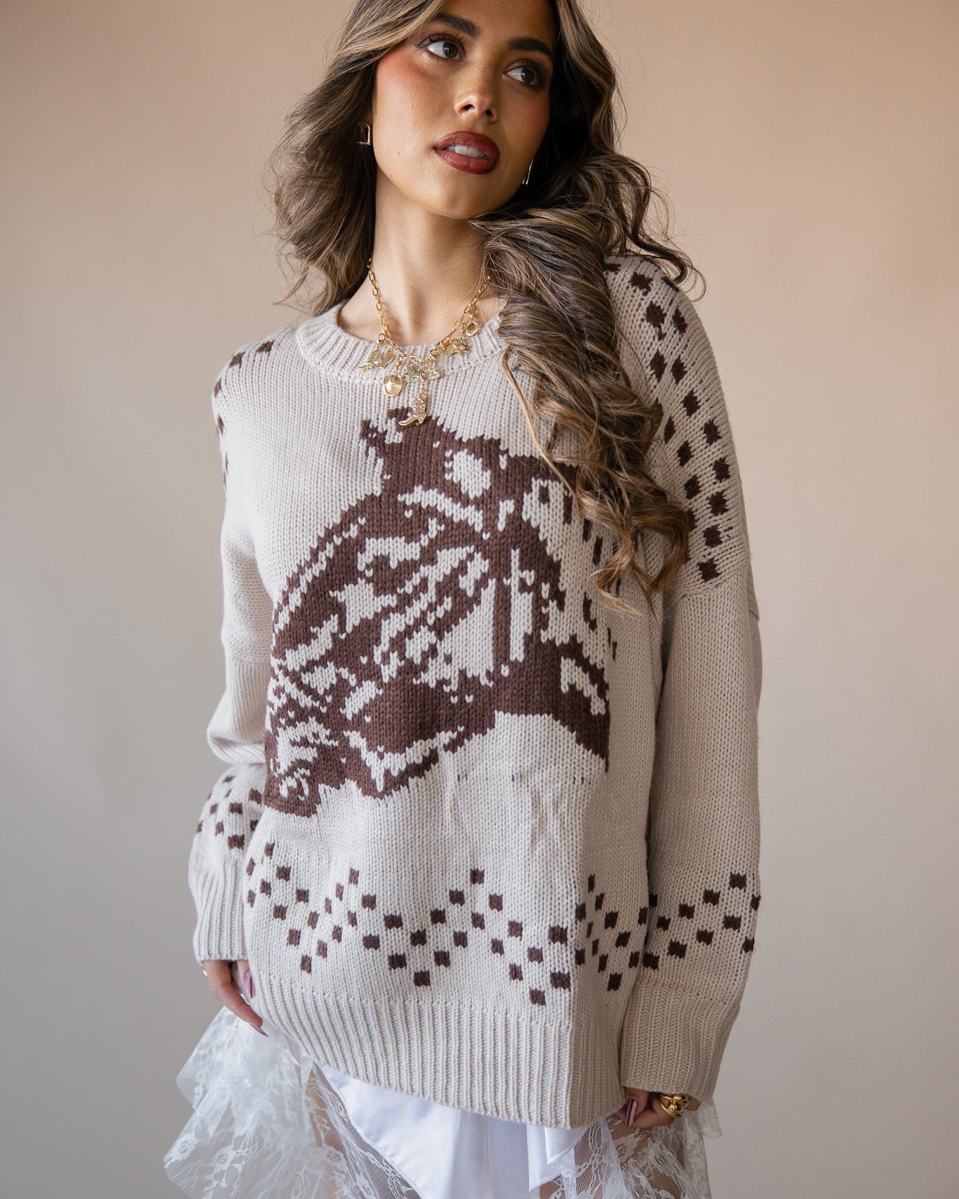 Woman in western knit sweater with brown graphic, paired with white lace skirt, boho style