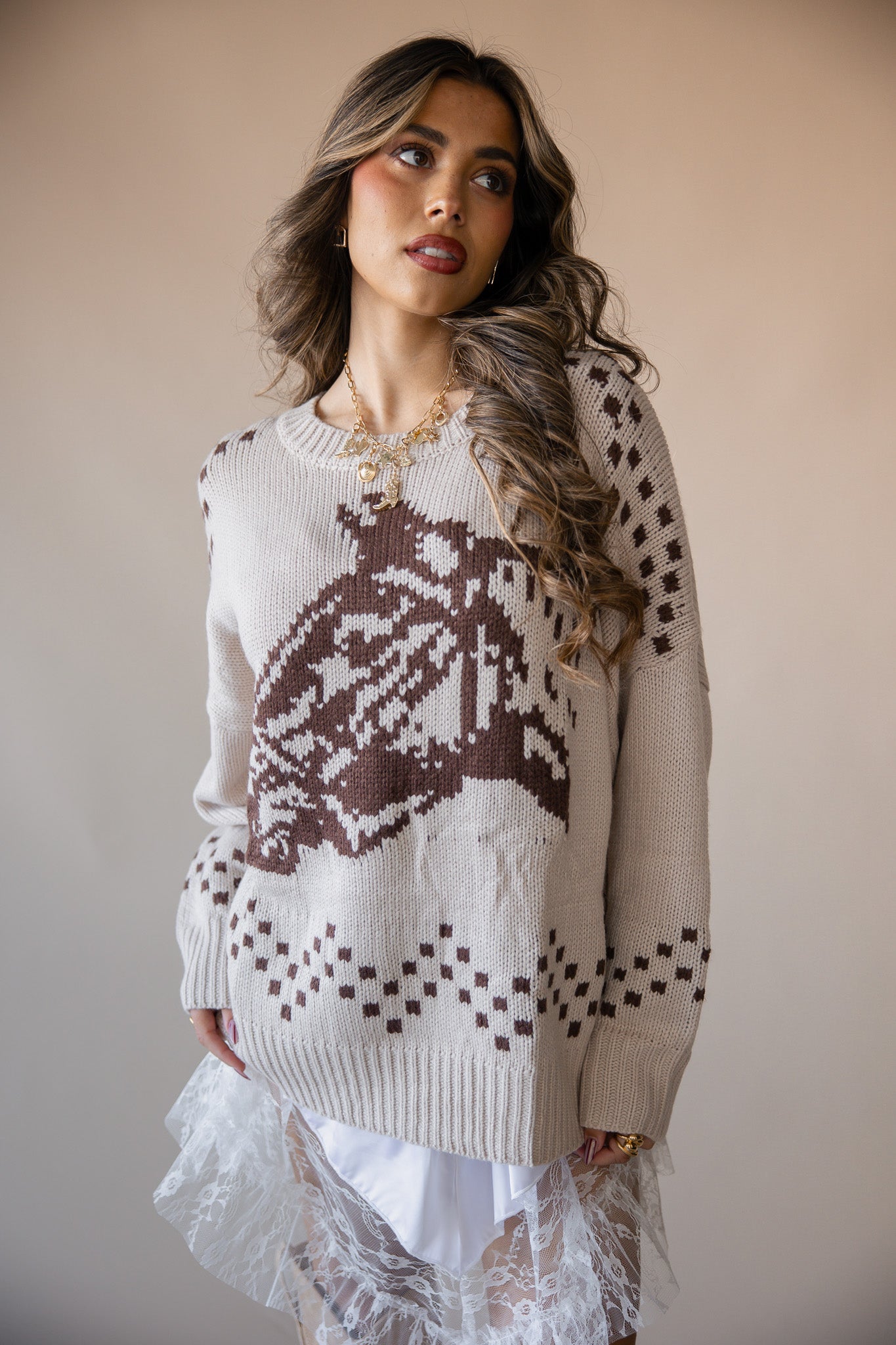 Woman in western knit sweater with brown graphic, paired with white lace skirt, boho style