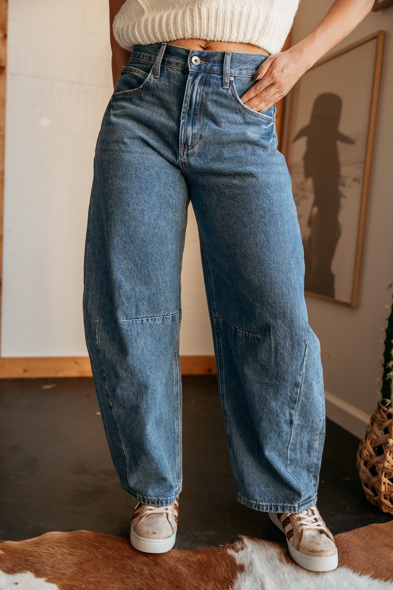 Woman wearing high-waisted wide leg denim jeans and cow print sneakers, western style