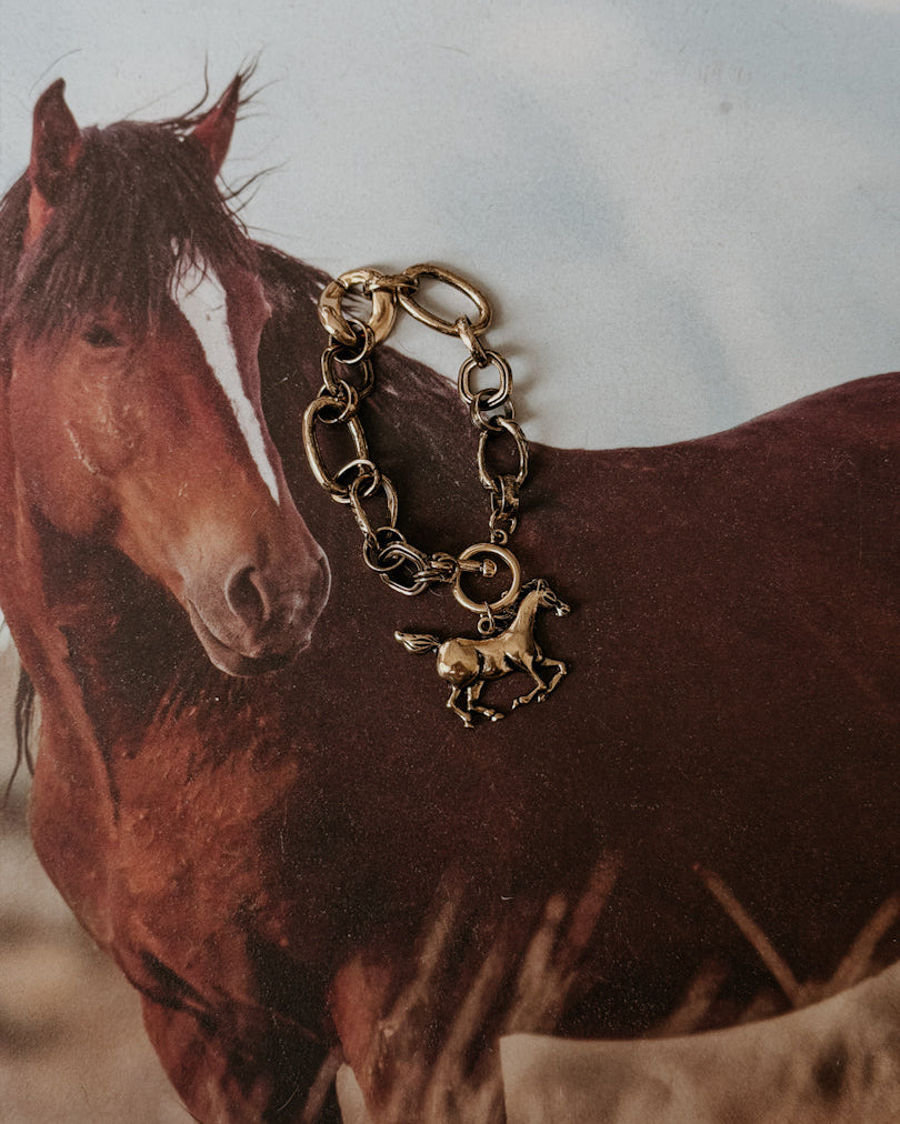Western horse charm bracelet on rustic horse background, boho cowgirl jewelry style