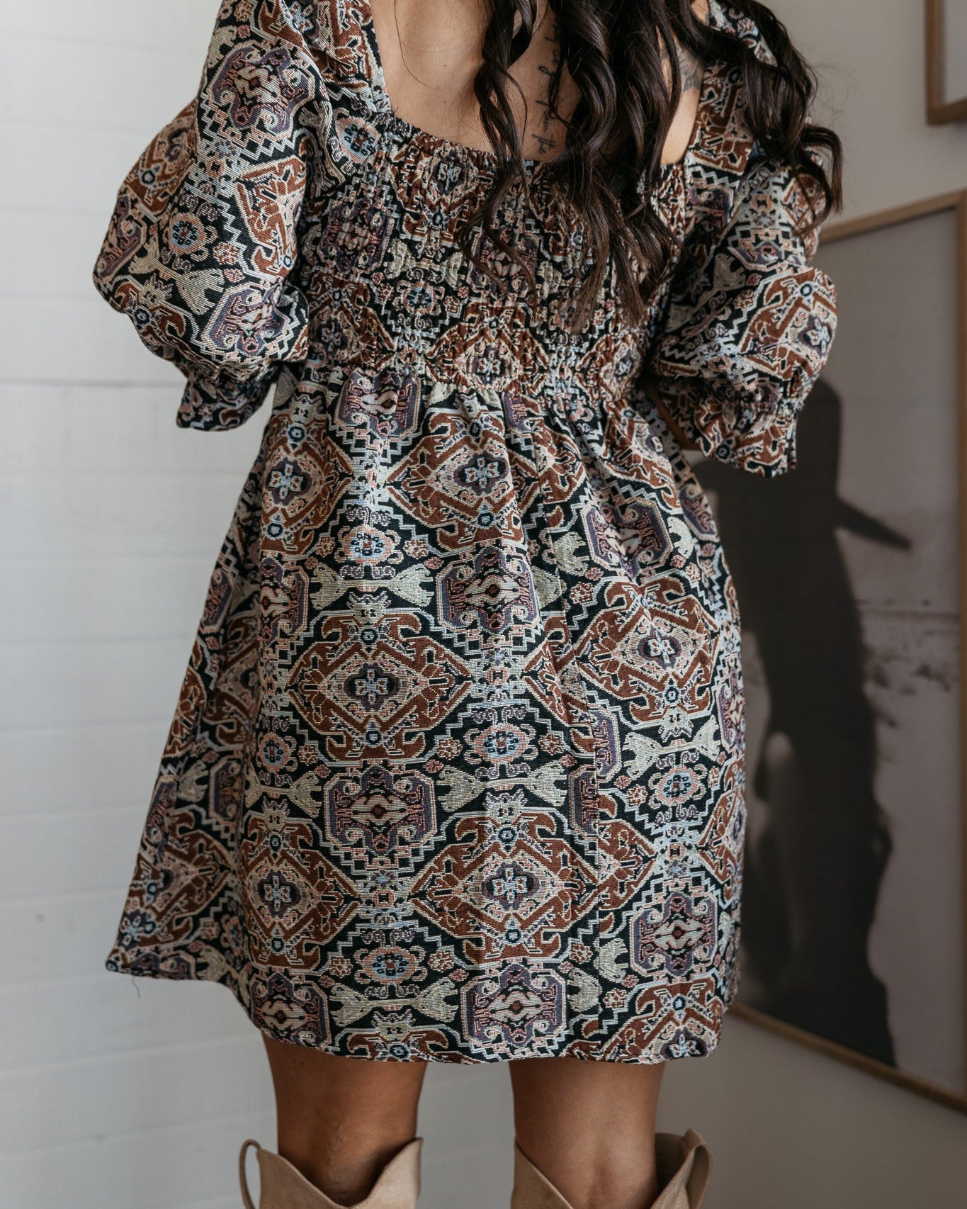 Woman in boho western patterned mini dress with puff sleeves and tan cowboy boots