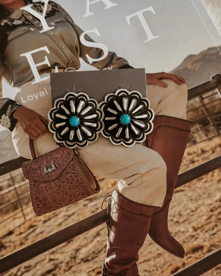 Western concho earrings with turquoise center on rodeo cowgirl magazine background