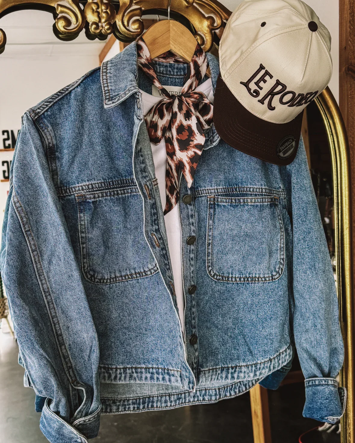 Denim western jacket with leopard print bandana and beige Le Rodeo cap on hanger