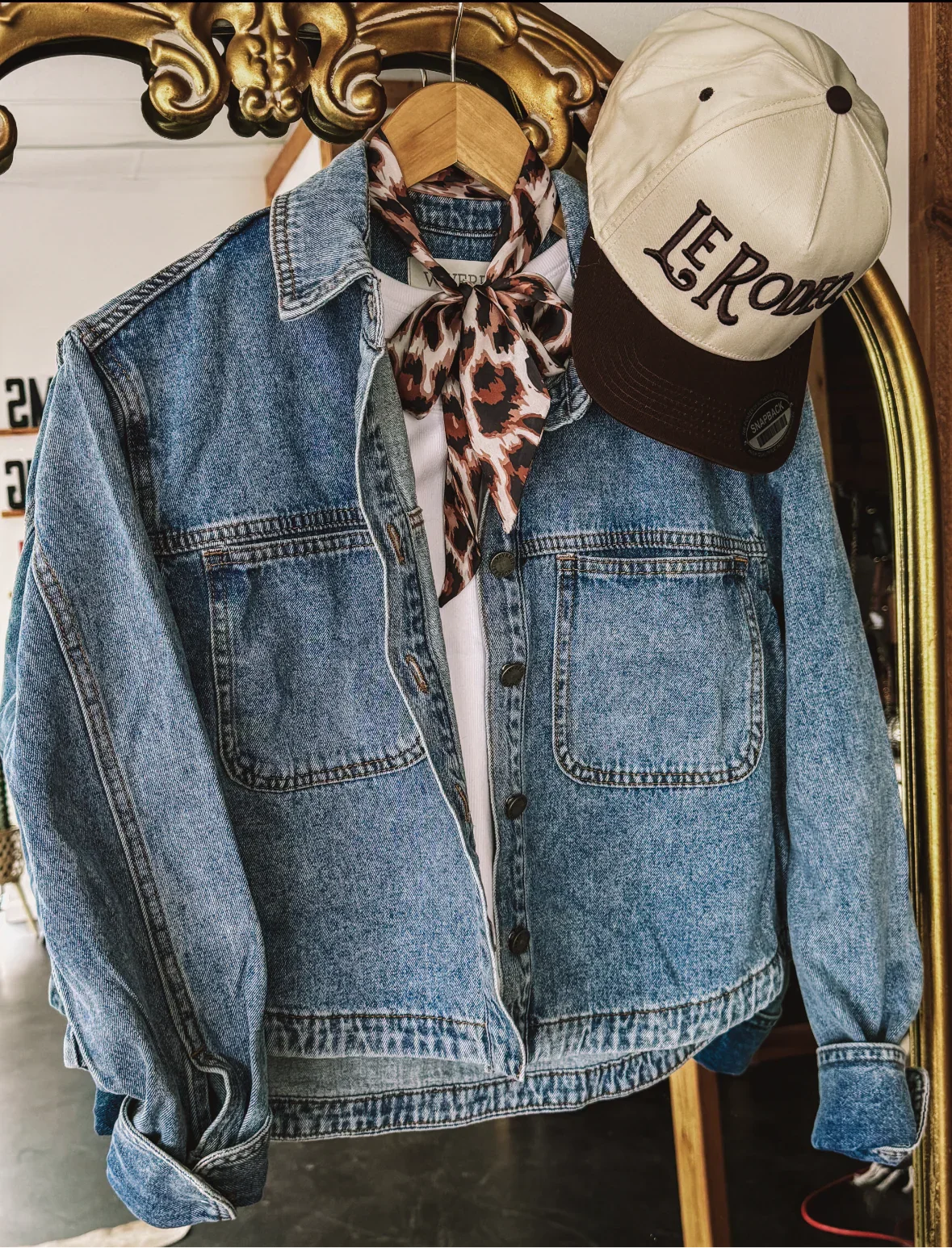 Denim western jacket with leopard print bandana and beige Le Rodeo cap on hanger