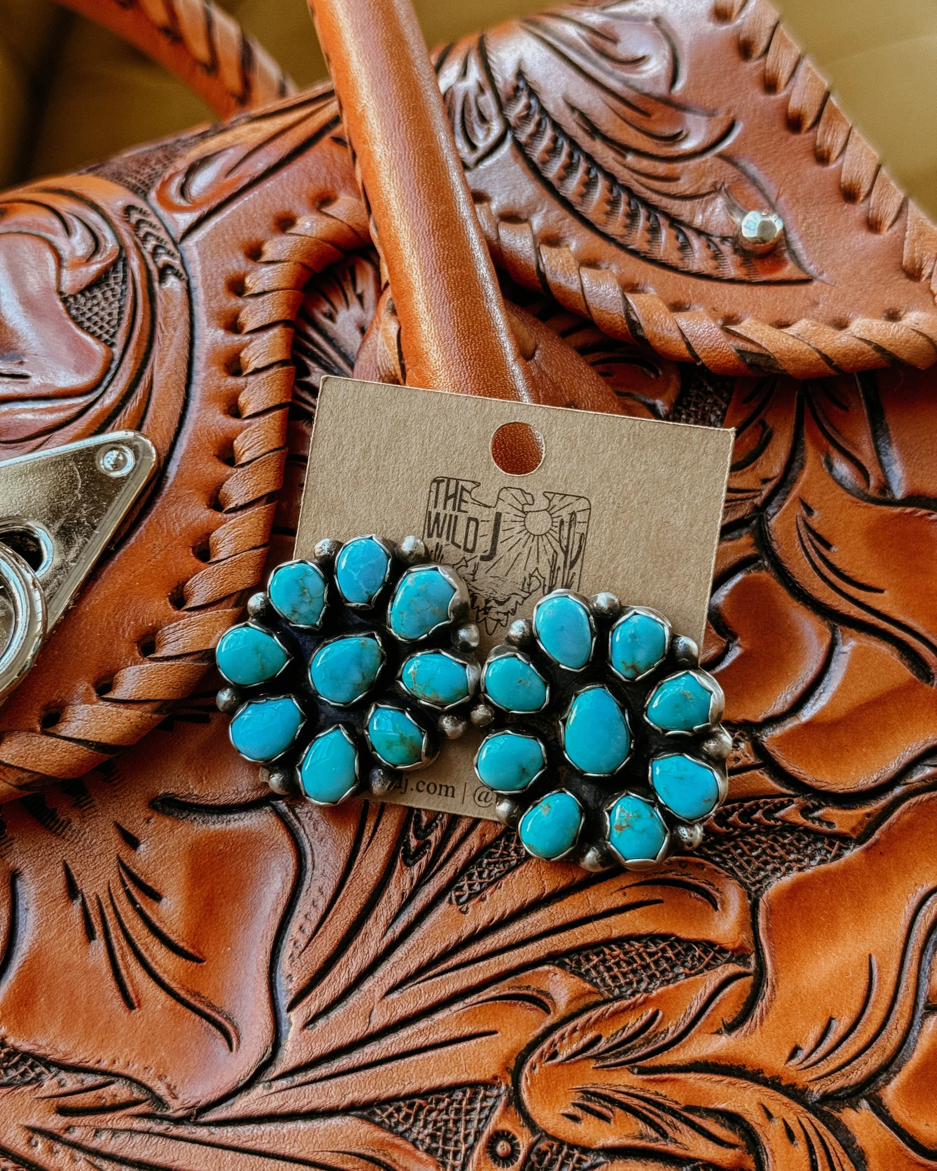 Turquoise cluster stud earrings on tooled leather western purse background