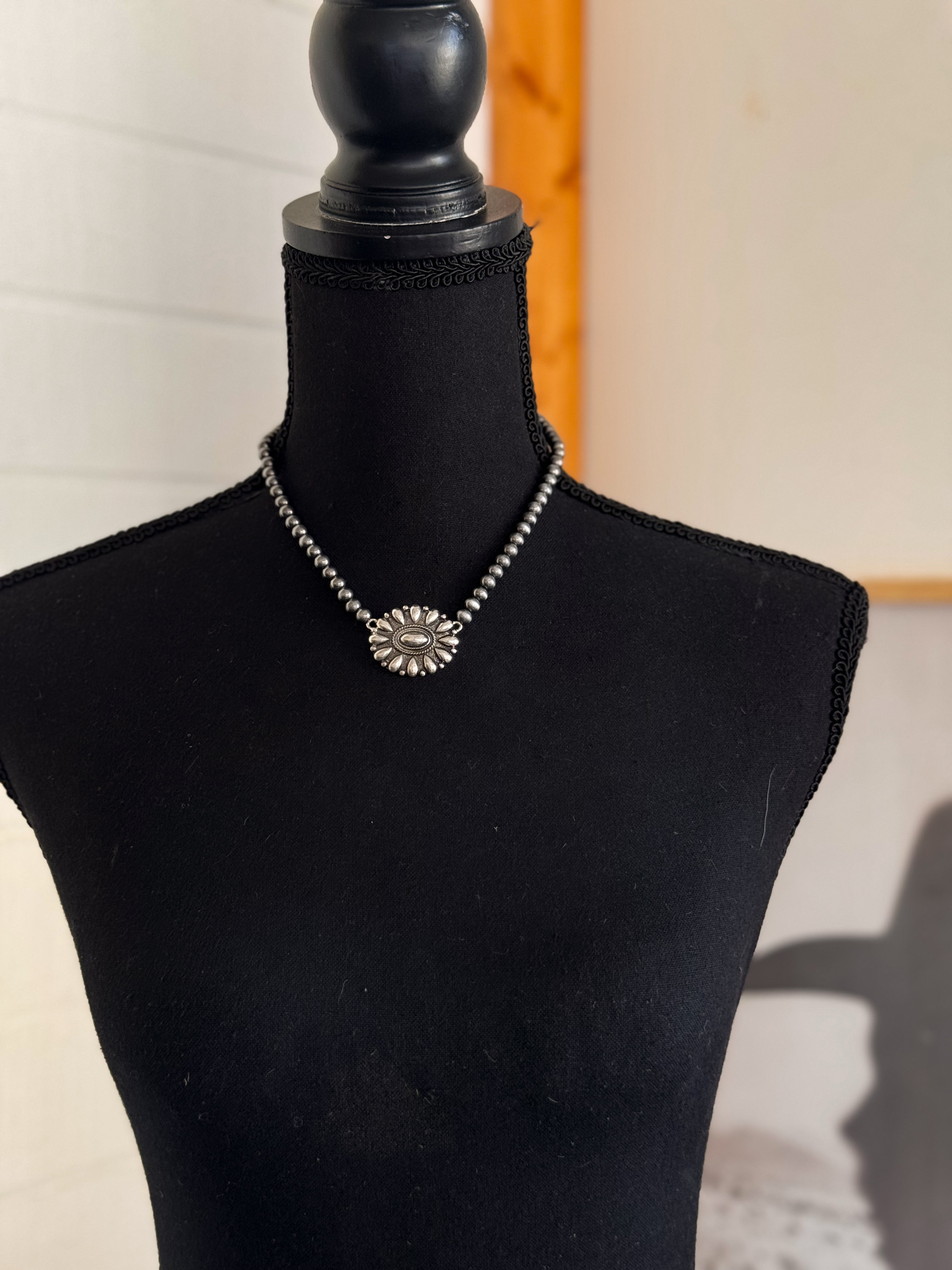 Thunderbird pendant chain necklace displayed on wooden slab with serape fabric underneath - The Wild J