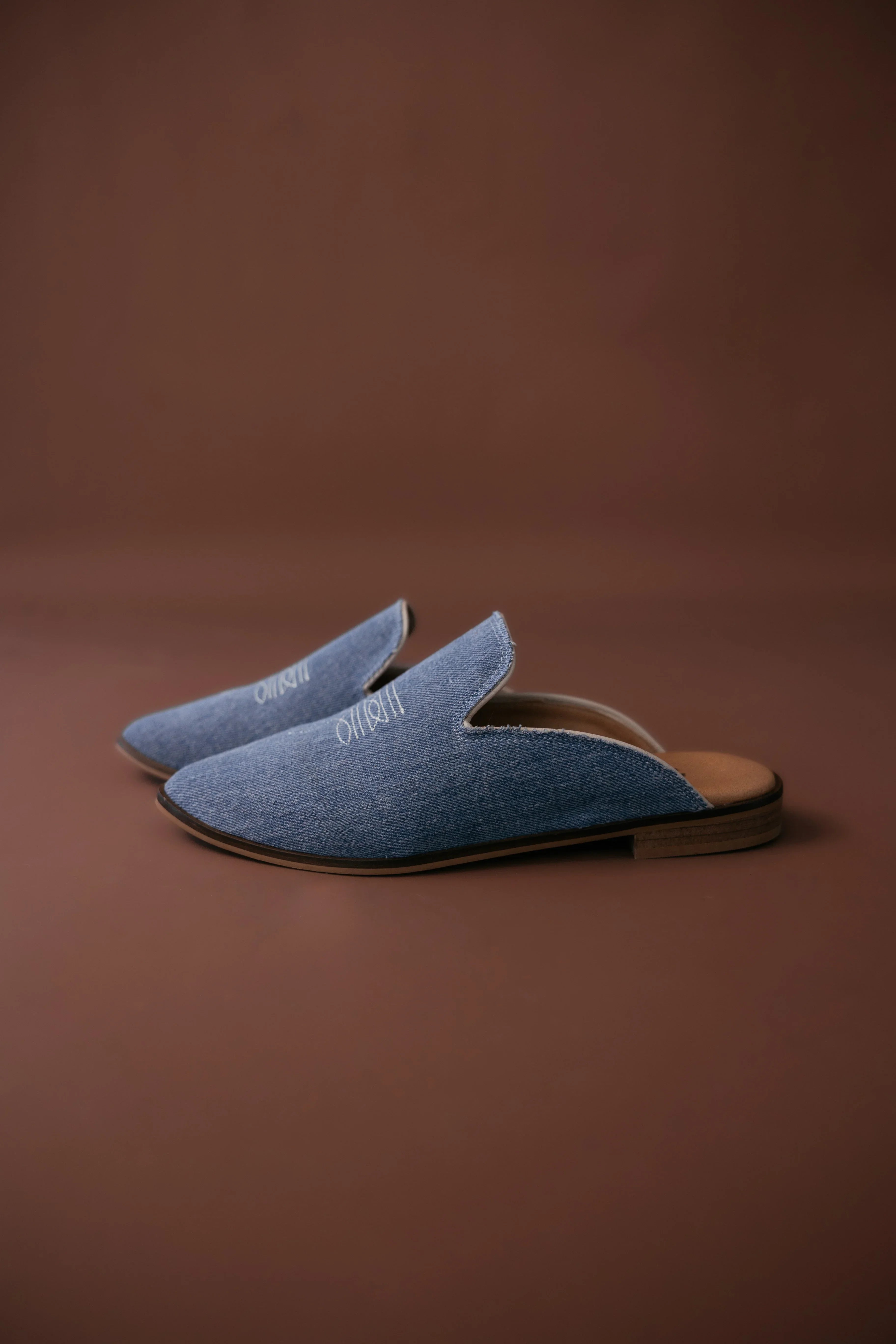 Pair of denim blue slippers on a brown background