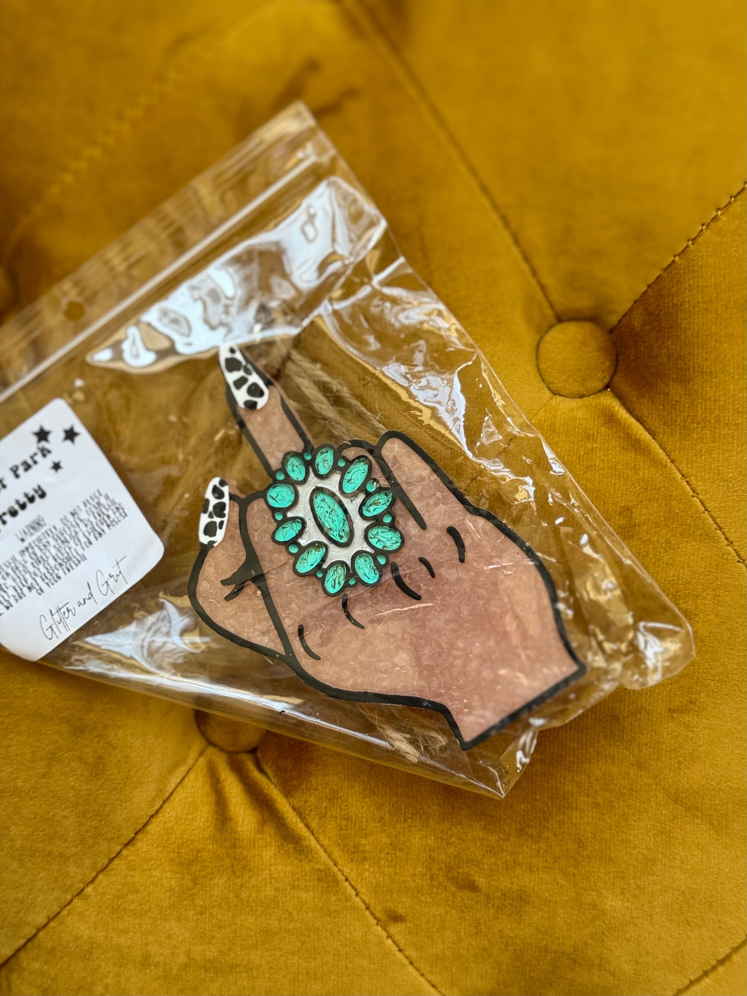 Western boho hand-shaped air freshener with turquoise ring on yellow tufted fabric.