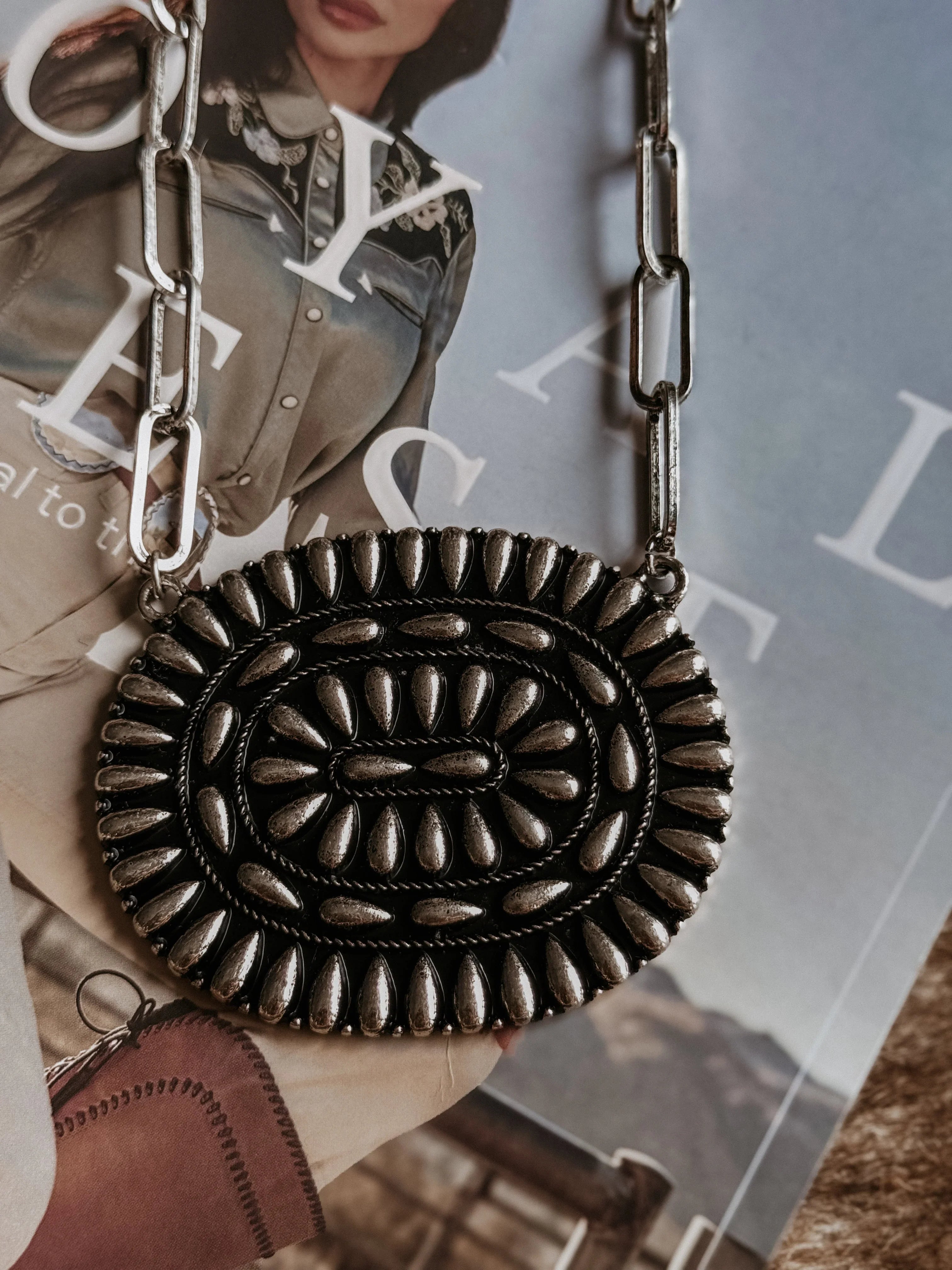 Decorative metal bag with chain strap on a magazine background