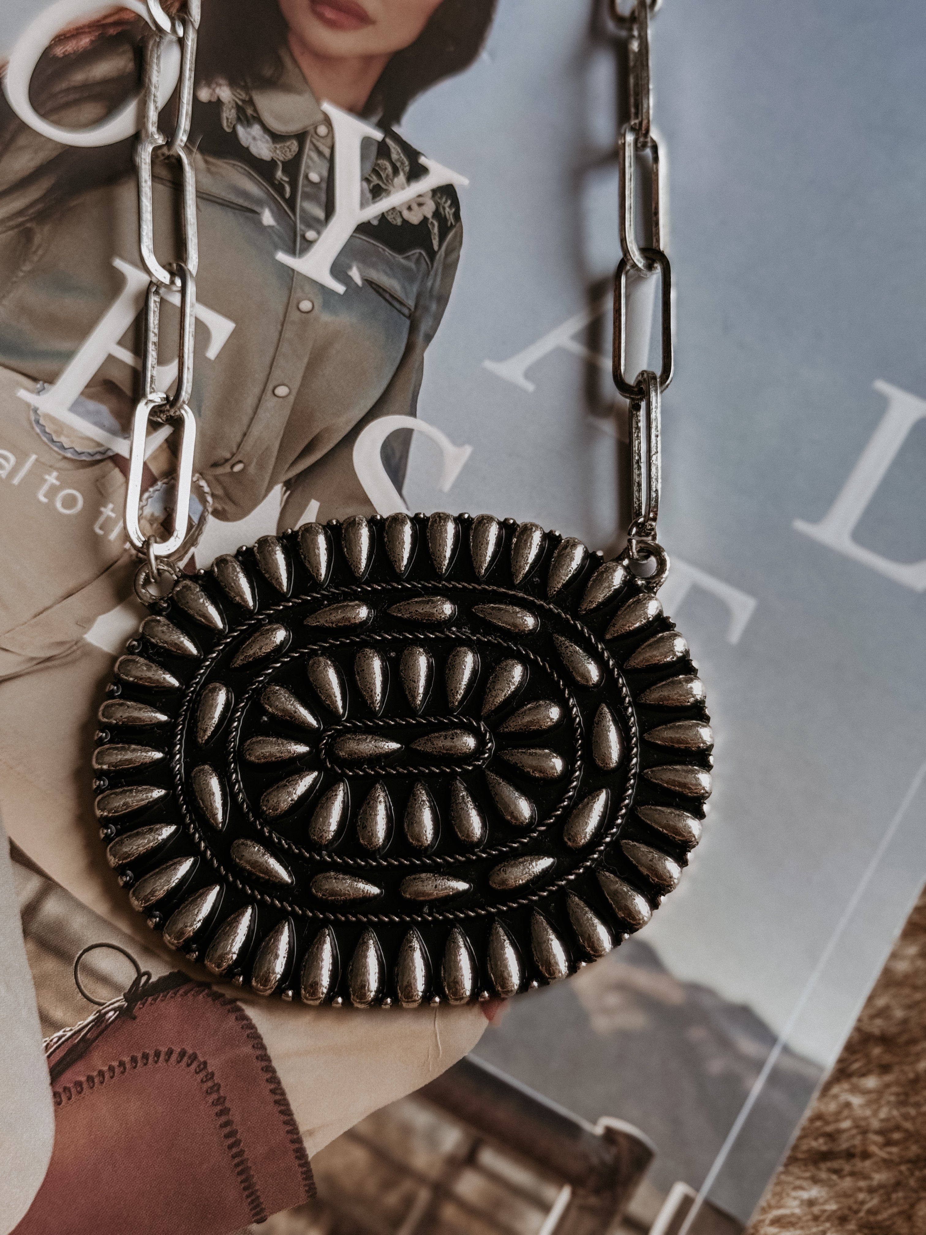 Thunderbird pendant chain necklace displayed on wooden slab with serape fabric underneath - The Wild J