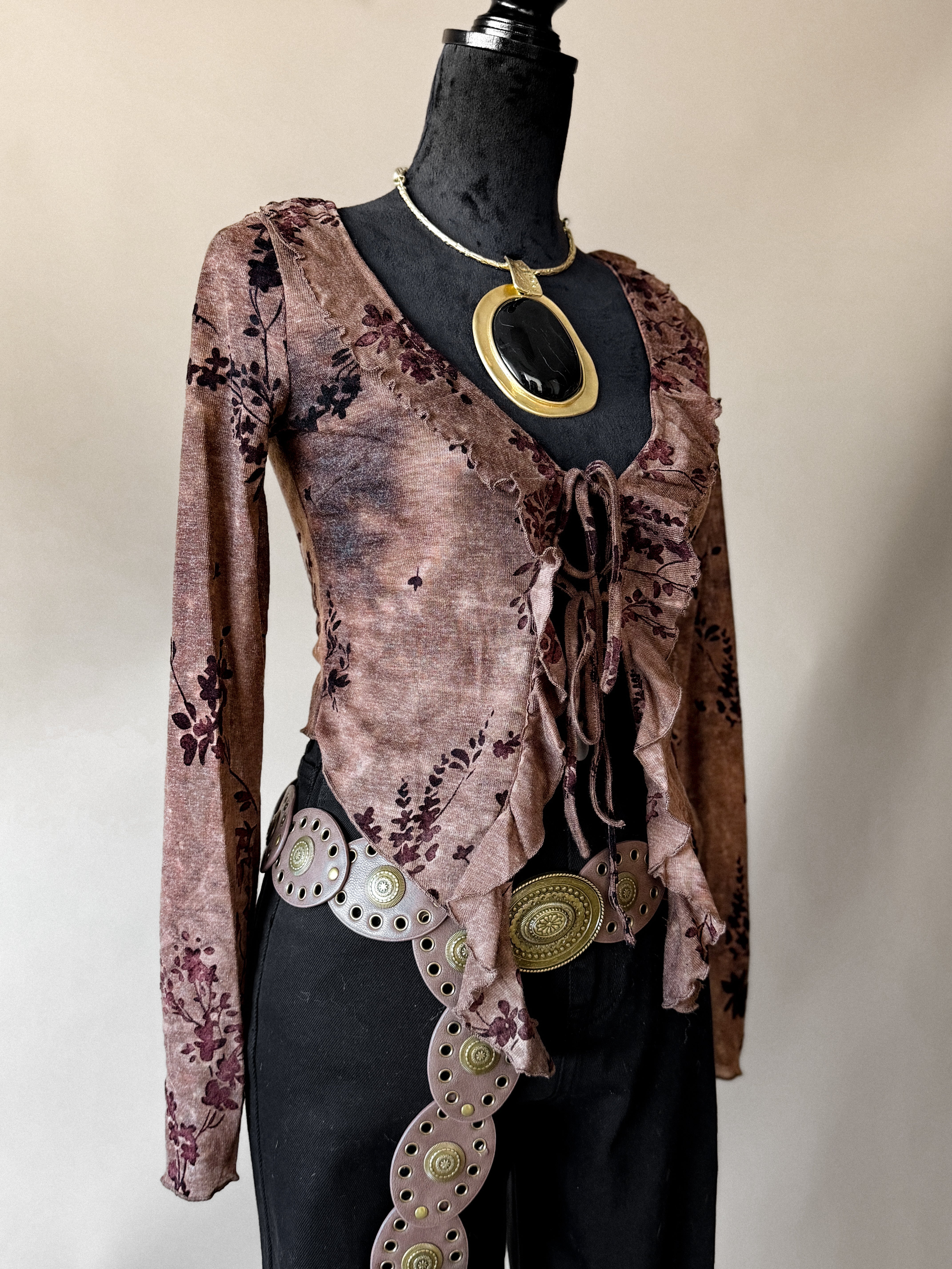 Mannequin wearing a brown patterned top with gold accents on a plain background