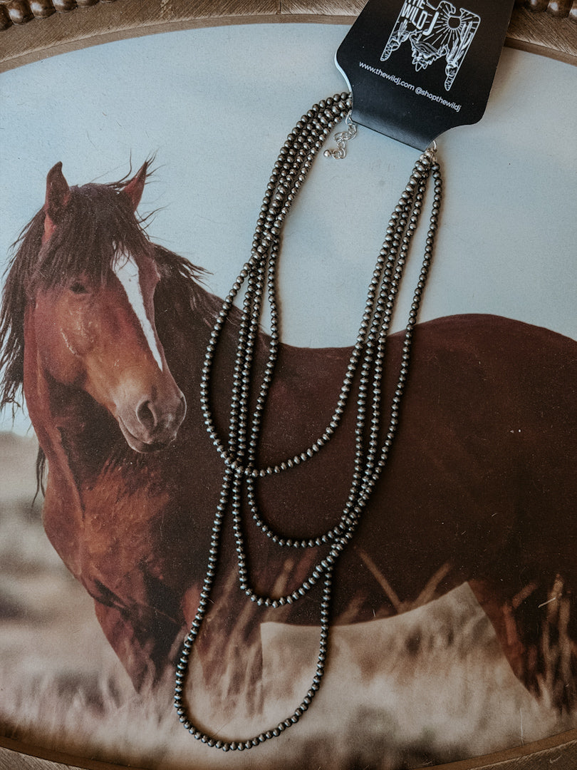 Thunderbird pendant chain necklace displayed on wooden slab with serape fabric underneath - The Wild J