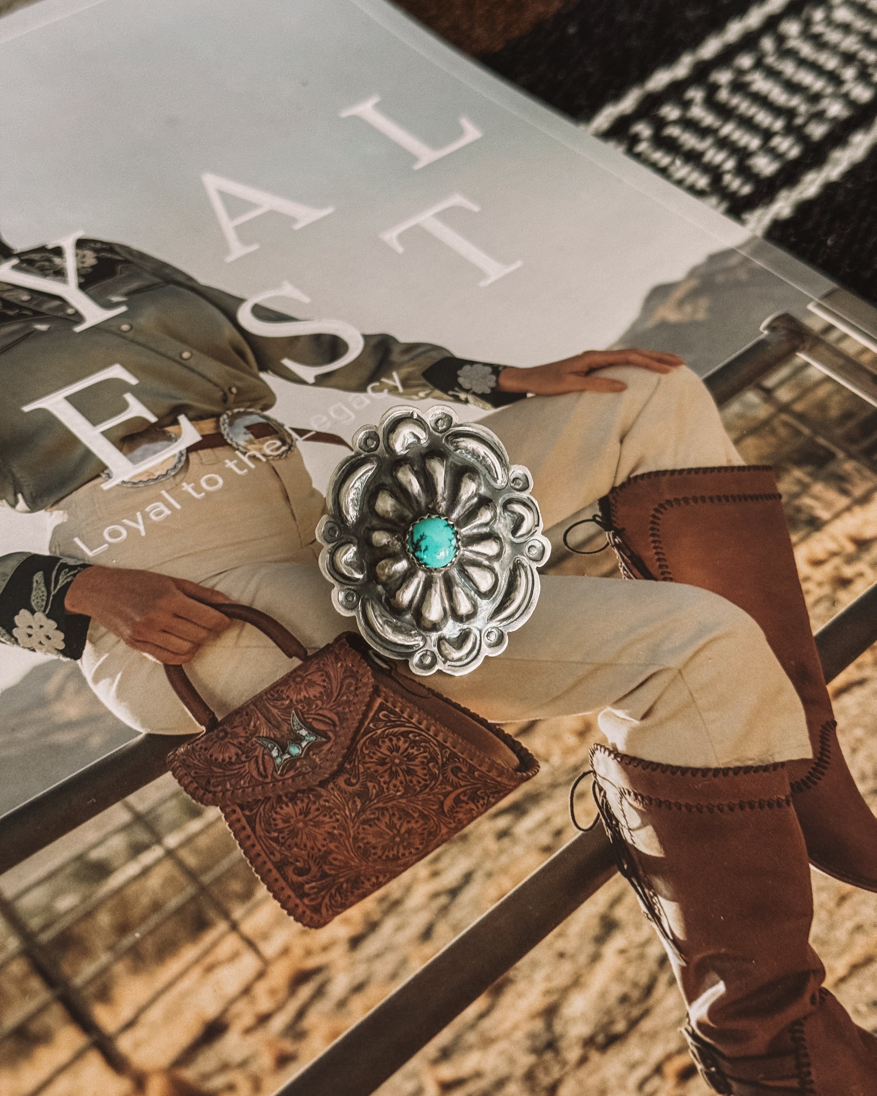 Silver Navajo concho ring with turquoise stone on western fashion magazine background