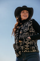 Woman in black cowboy hat and patterned western vest, western boho street style