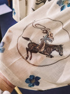 Thunderbird pendant chain necklace displayed on wooden slab with serape fabric underneath - The Wild J