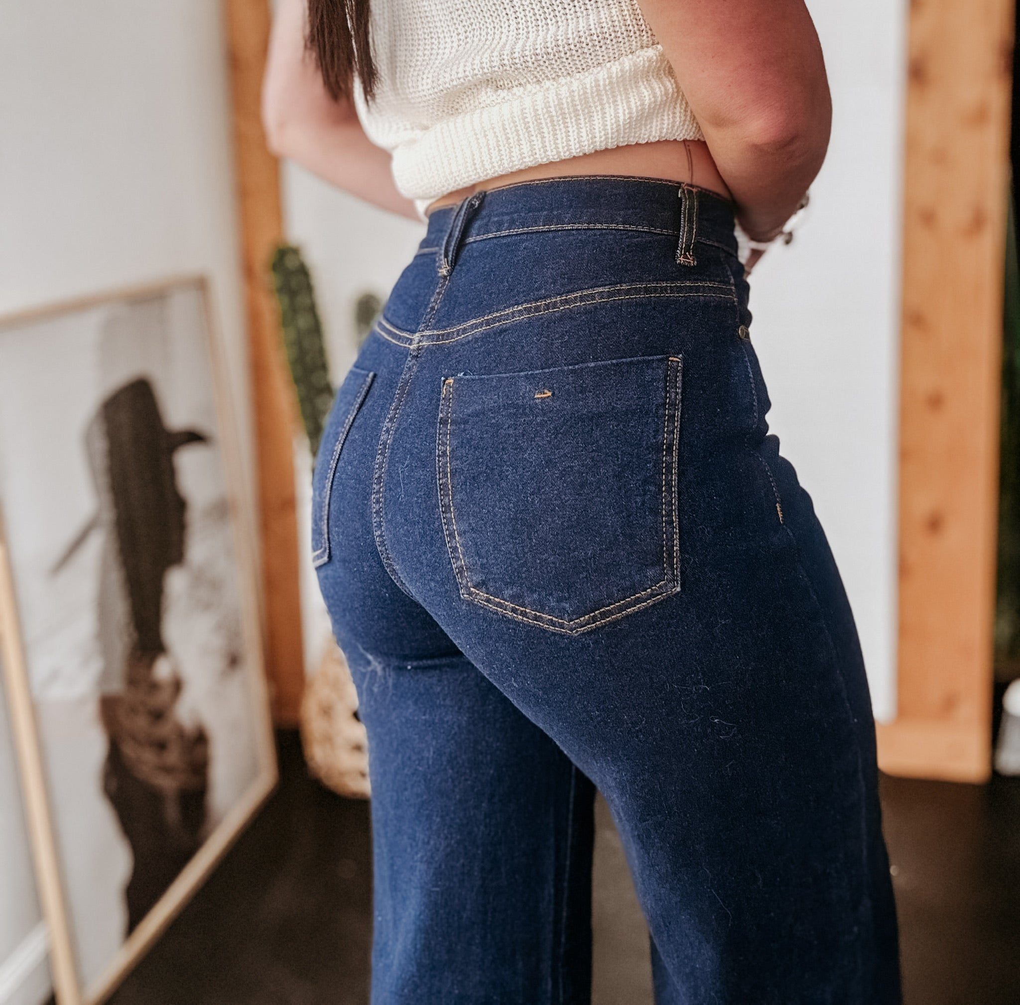 High-waisted dark blue flare jeans styled with a cropped knit top, western boho decor background