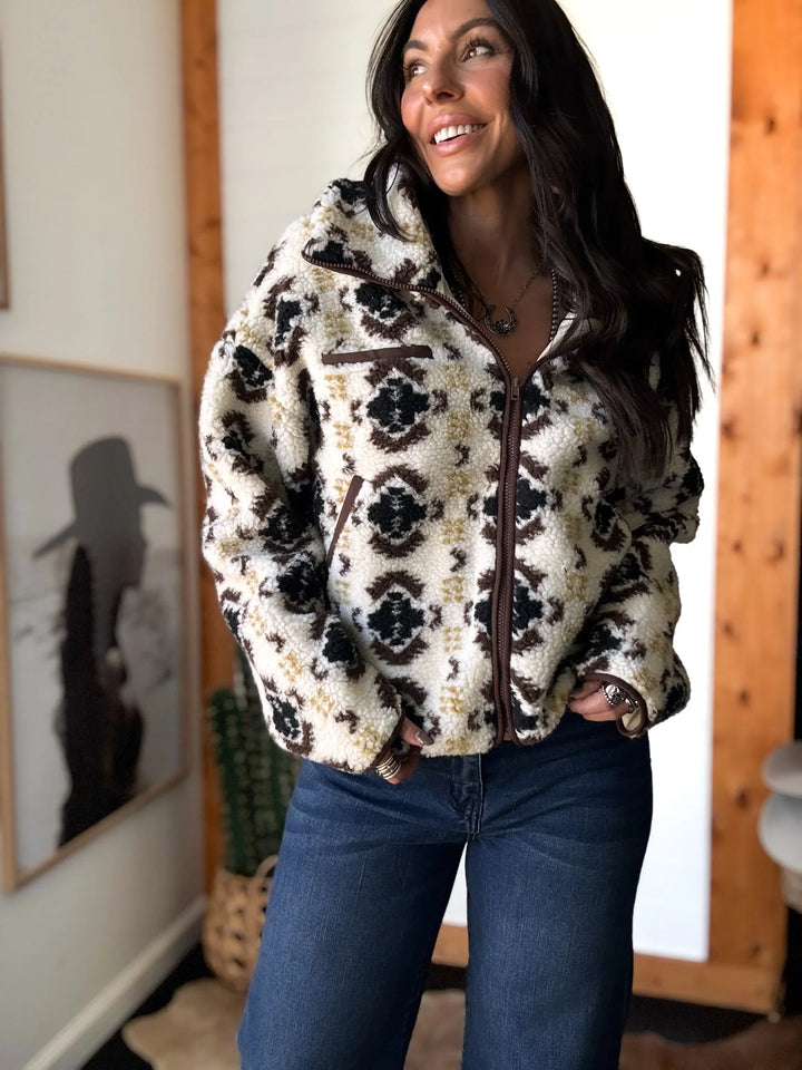 Woman wearing a patterned jacket indoors with a neutral background
