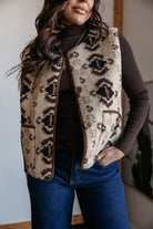 Woman wearing a western boho sherpa vest with tribal print, brown turtleneck, and blue jeans