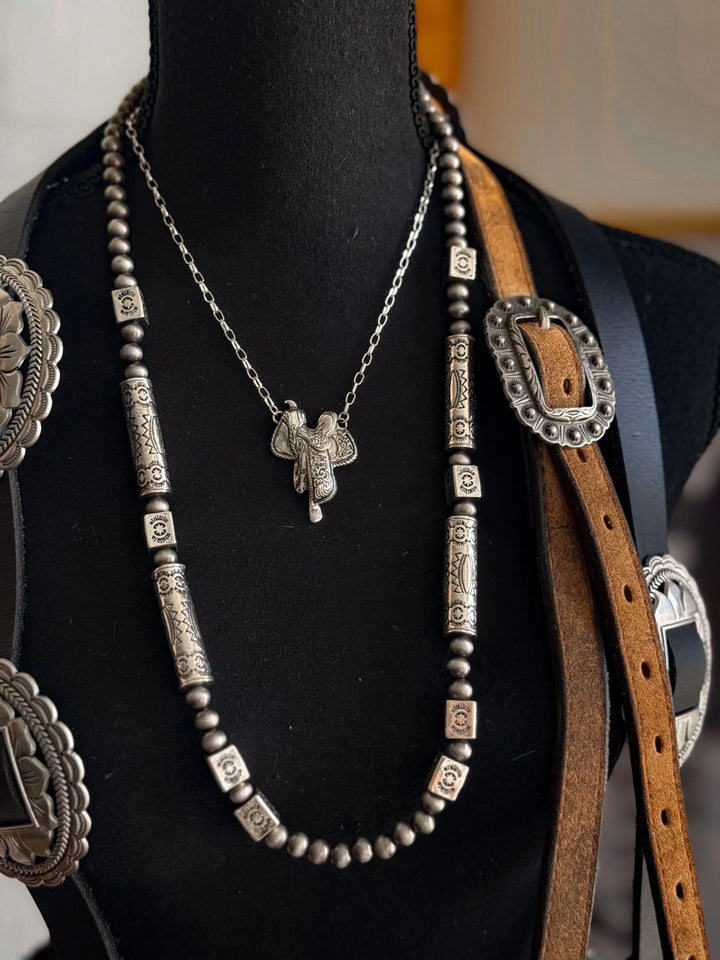 Necklace with pendant and belt with conchos on a black mannequin