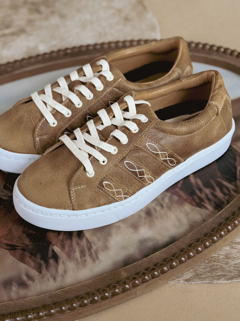 Tan western boho sneakers with white laces and embroidery on rustic decorative tray