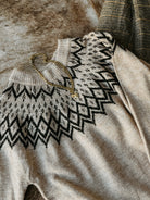 Beige sweater with black pattern on a textured surface