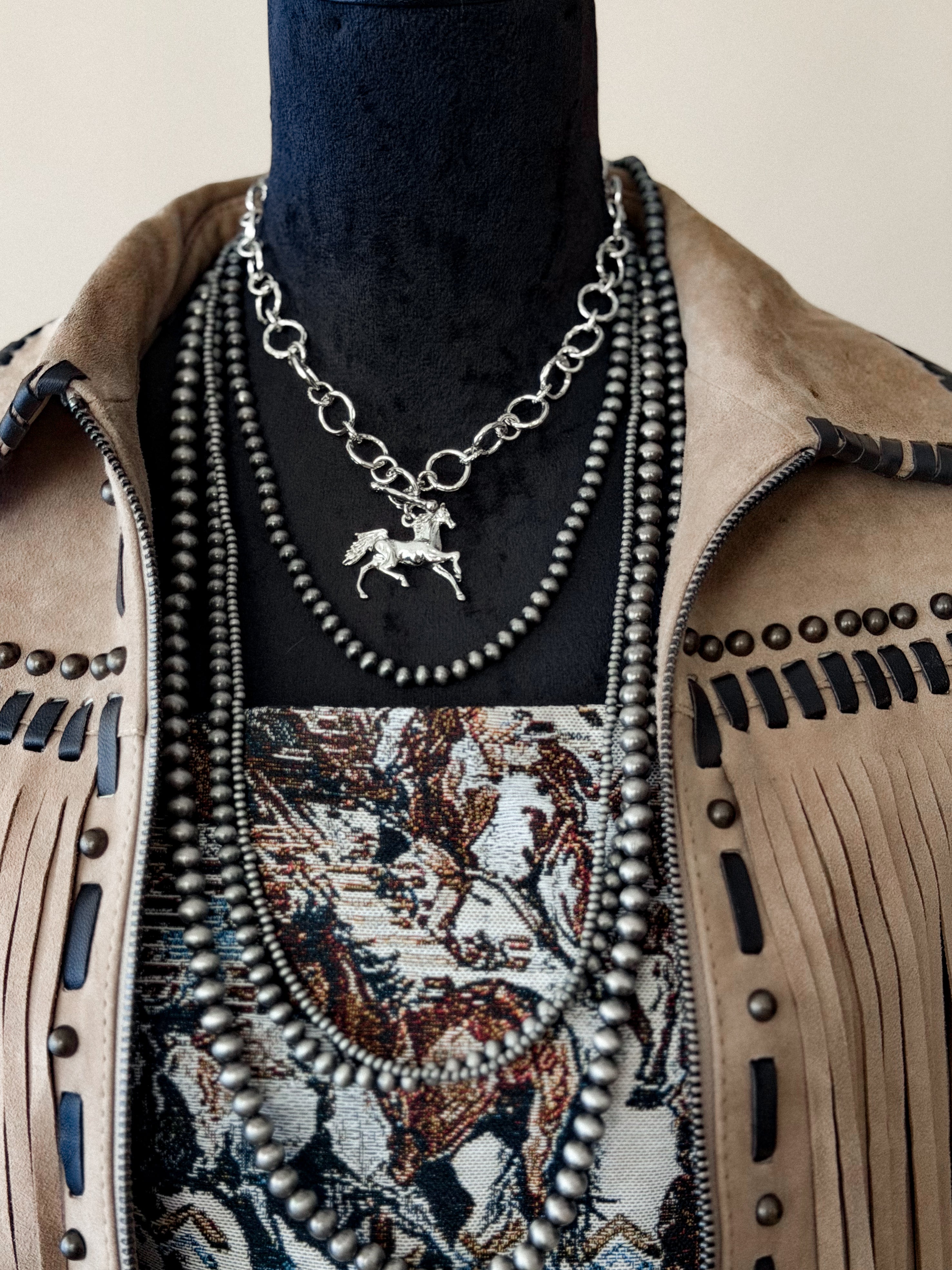 Thunderbird pendant chain necklace displayed on wooden slab with serape fabric underneath - The Wild J