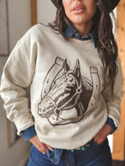 Woman in western hat and denim shirt wearing cream horse graphic sweatshirt, boho western style
