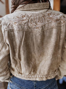 Western denim jacket with floral embroidery and horseshoe details, styled with blue jeans.