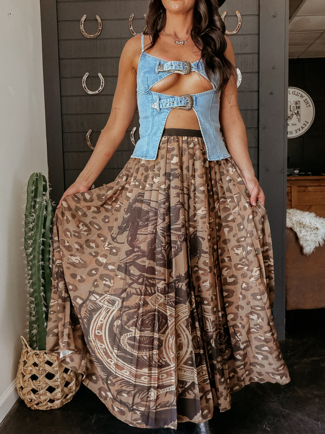 Woman wearing a denim top and patterned skirt in a room with a cactus plant.