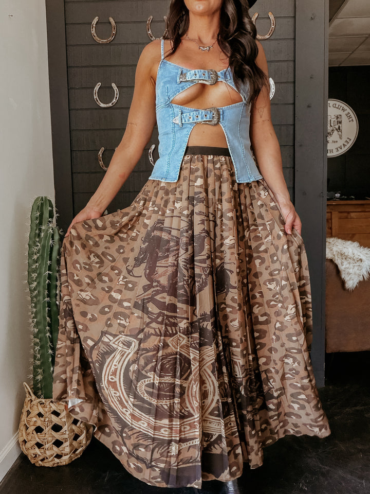 Woman wearing a denim top and patterned skirt in a room with a cactus plant.