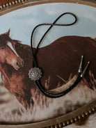 Thunderbird pendant chain necklace displayed on wooden slab with serape fabric underneath - The Wild J