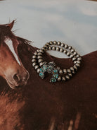 Thunderbird pendant chain necklace displayed on wooden slab with serape fabric underneath - The Wild J