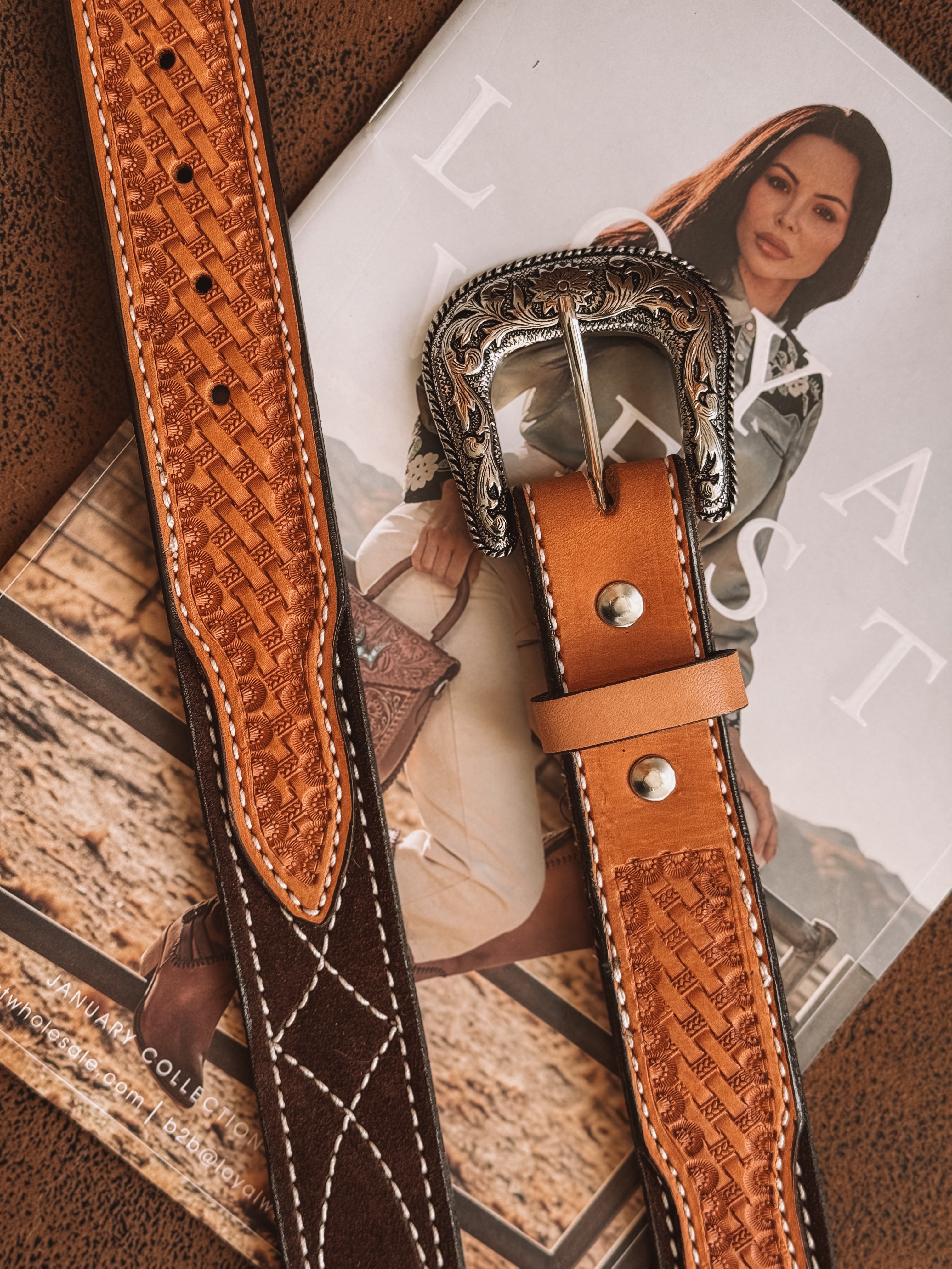 Tooled leather western belt with ornate silver buckle on a magazine with cowgirl fashion model