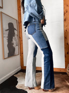Woman wearing colorblock denim flare jeans and western boots in rustic room