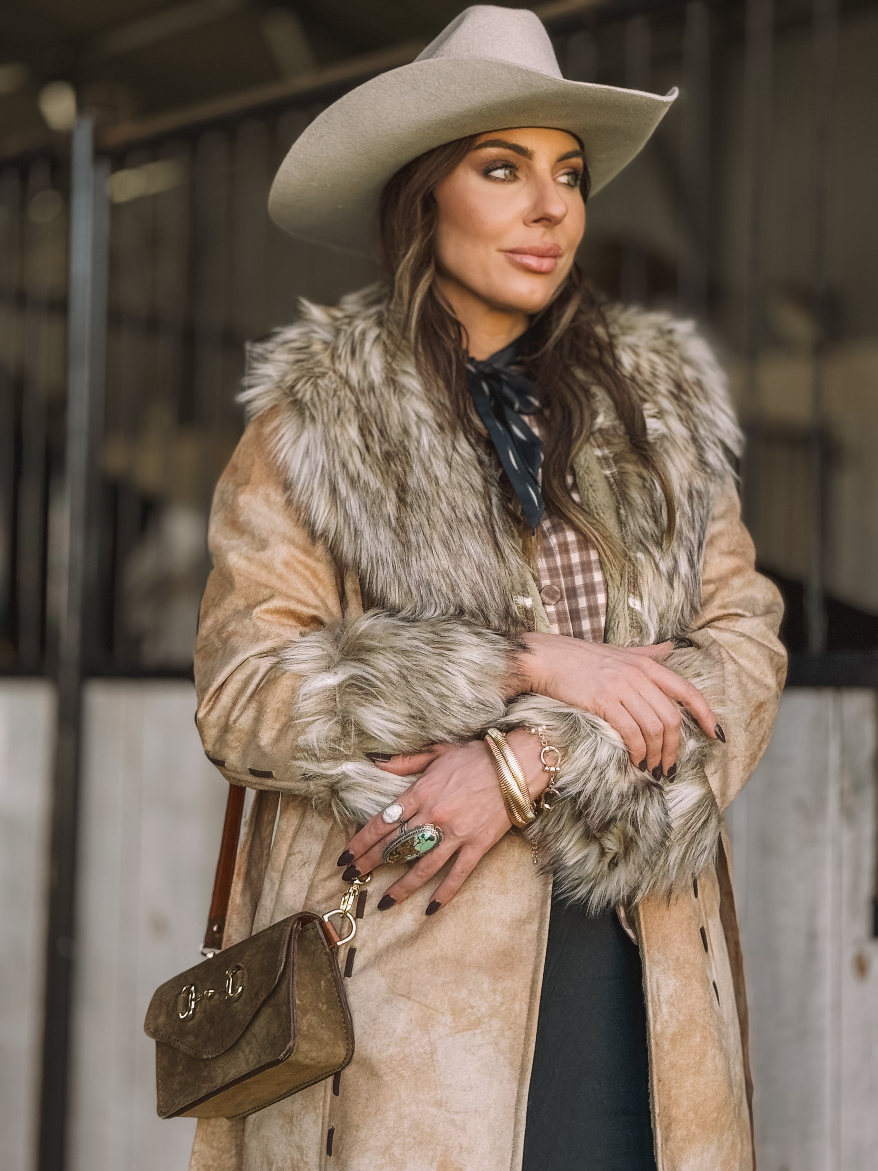 Woman in a faux fur western coat, cowboy hat, and gemstone jewelry, western boho style