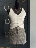 Mannequin wearing a white ribbed tank top and zebra print skirt against a dark background with horseshoes.