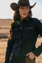 Woman in dark denim western jacket and cowboy hat outdoors, western boho fashion style