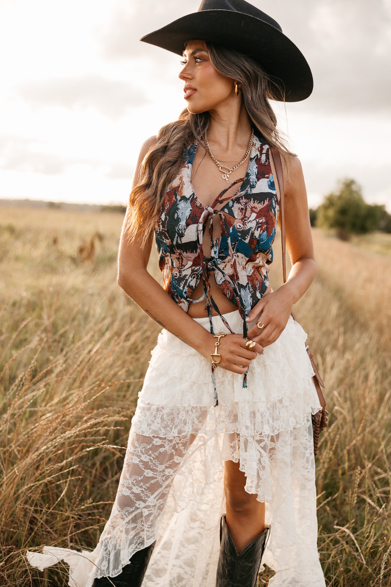 women wearing tie front halter top with horse pattern and a white skirt standing in a field. 