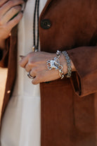 Woman wearing western silver bracelets and brown suede jacket, cowgirl boho jewelry style