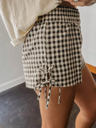Person wearing a black and white checkered skirt with a tie waist.