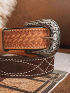 Tooled leather western belt with ornate silver buckle and stitched brown suede overlay