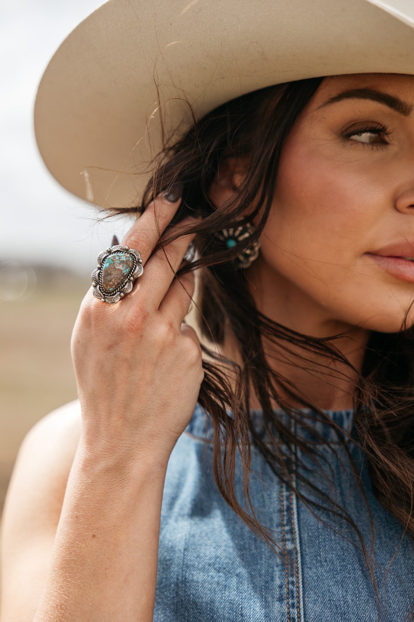 Woman in a cowboy hat wearing boho turquoise ring and denim top, western jewelry style