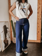 Woman in western graphic sleeveless top and high-waisted flared jeans with turquoise jewelry