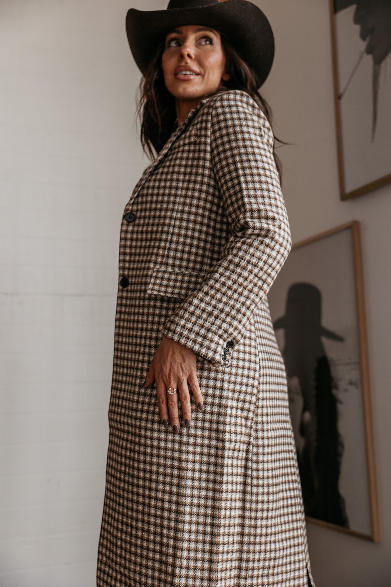 Woman in brown checkered long western coat and black cowboy hat, boho western fashion